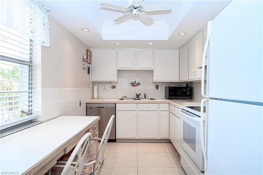 1280 Blue Point Avenue, Unit C30 Naples, FL 34102 - Photo 6 of 24 a kitchen with white cabinets and white appliances