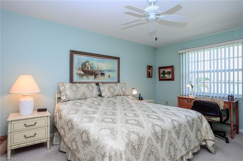 1280 Blue Point Avenue, Unit C30 Naples, FL 34102 - Photo 10 of 24 a bedroom with a bed and a chandelier