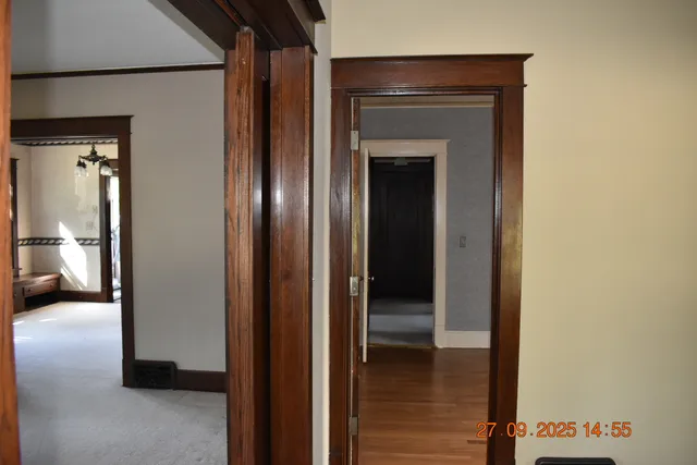 a view of a hallway with wooden floor and a bathroom