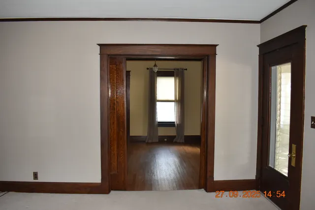a view of a hallway with wooden floor and a living room