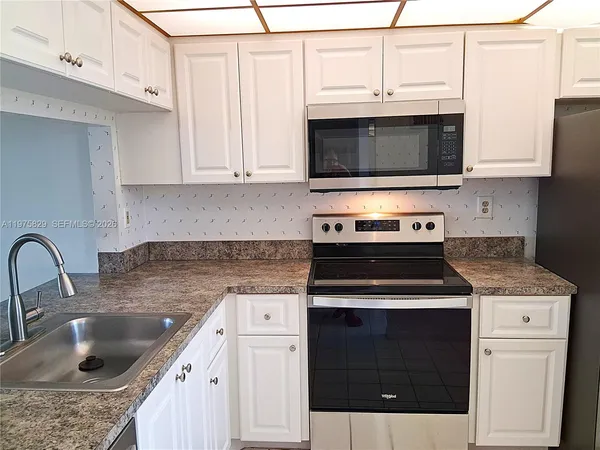 a kitchen with stainless steel appliances granite countertop a sink a refrigerator and a granite counter tops