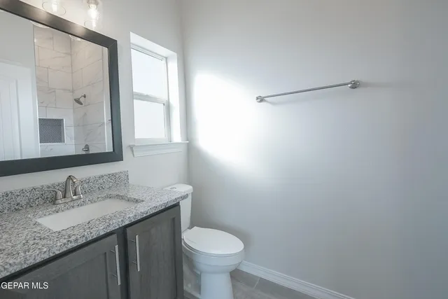 a bathroom with a granite countertop sink a toilet and a mirror