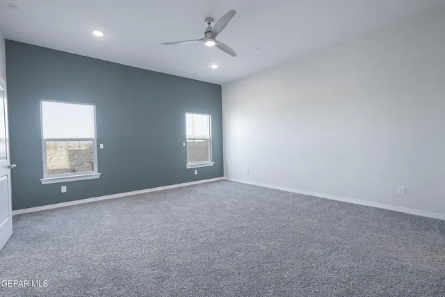 an empty room with windows and ceiling fan