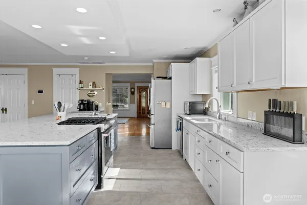 a kitchen with stainless steel appliances granite countertop a refrigerator sink and white cabinets