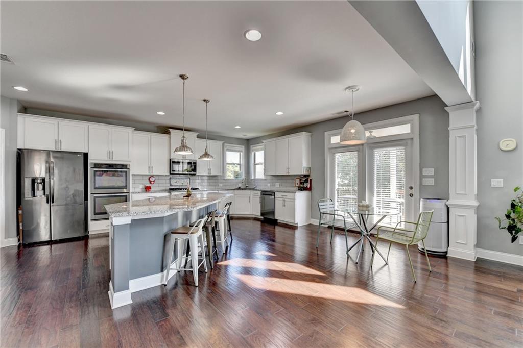 4071 Woodward Walk Lane Suwanee, GA 30024 - Photo 15 of 50 an open kitchen with kitchen island wooden floor and stainless steel appliances