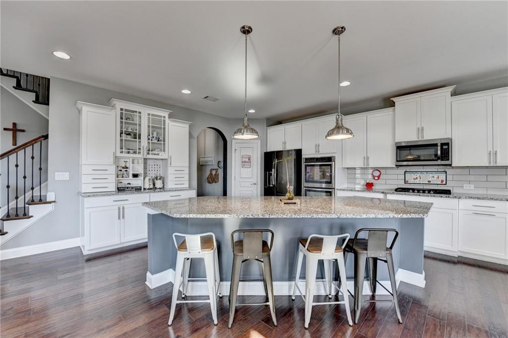 4071 Woodward Walk Lane Suwanee, GA 30024 - Photo 16 of 50 a large kitchen with cabinets chairs and stainless steel appliances