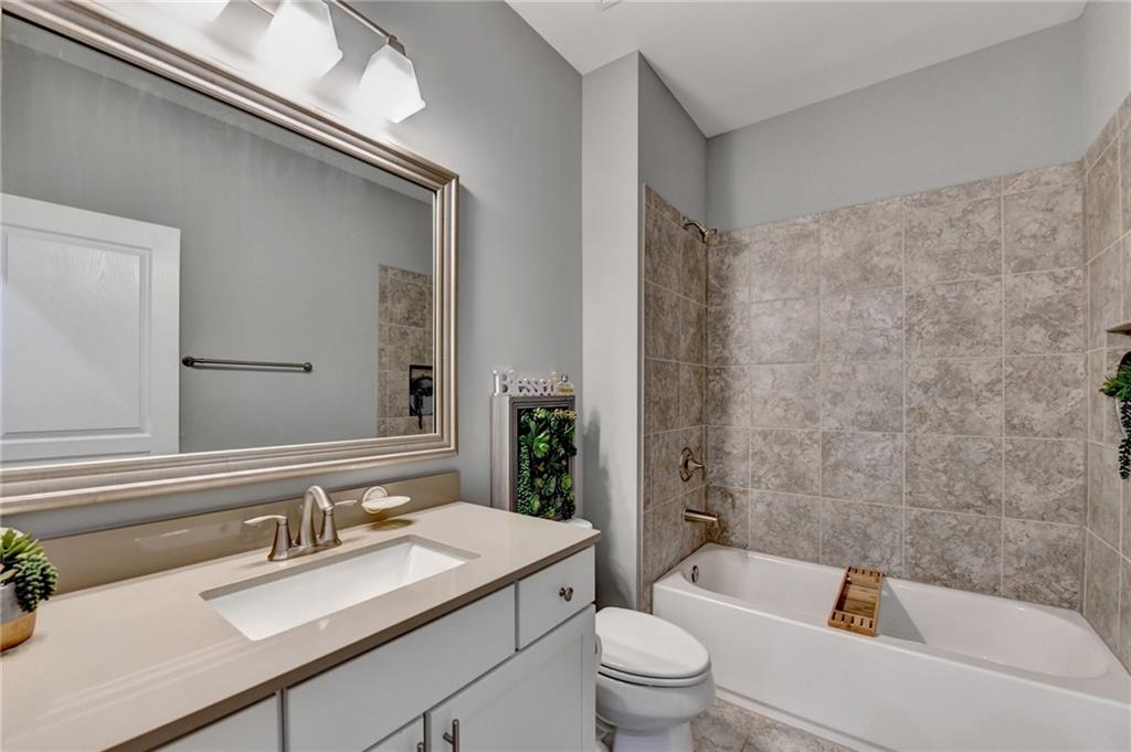 4071 Woodward Walk Lane Suwanee, GA 30024 - Photo 9 of 50 a bathroom with a granite countertop sink a toilet a mirror and bathtub