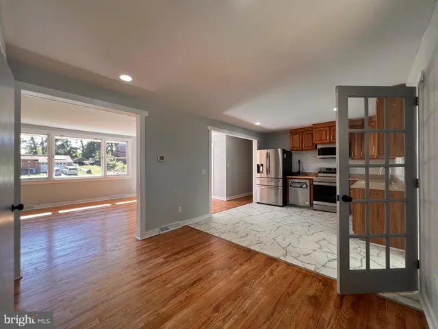 a view of a kitchen with wooden floor electronic appliances and windows