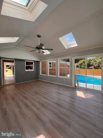 a view of an empty room with window and wooden floor