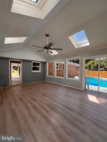 a view of an empty room with window and wooden floor