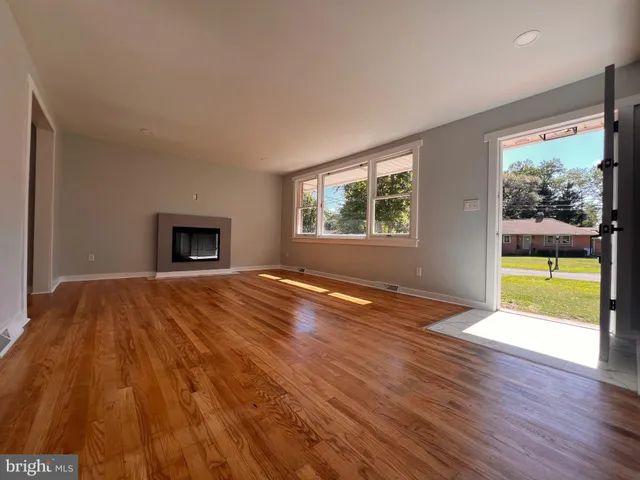 a view of empty room with wooden floor and fireplace