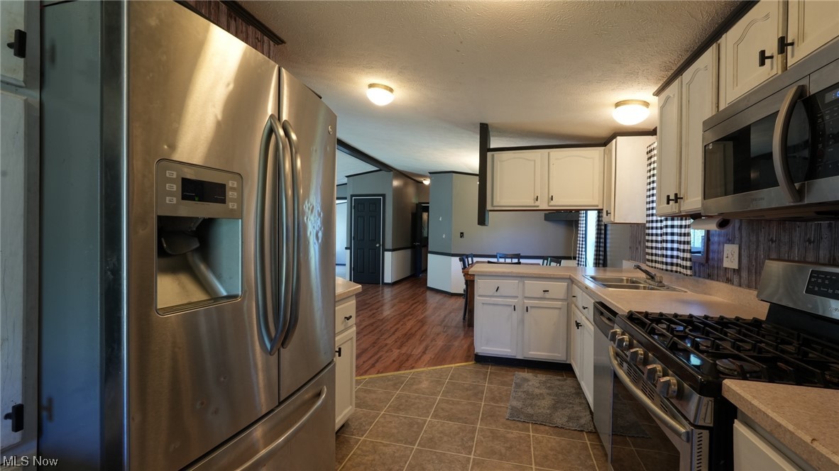 70871 Angus Road Cambridge, OH 43725 - Photo 17 of 29 Kitchen with dark tile floors, stainless steel appliances, light countertops, and white cabinetry