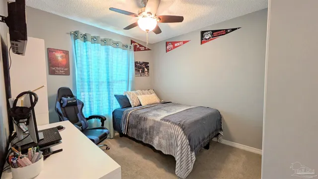 a bedroom with bed a flat tv screen and a dresser