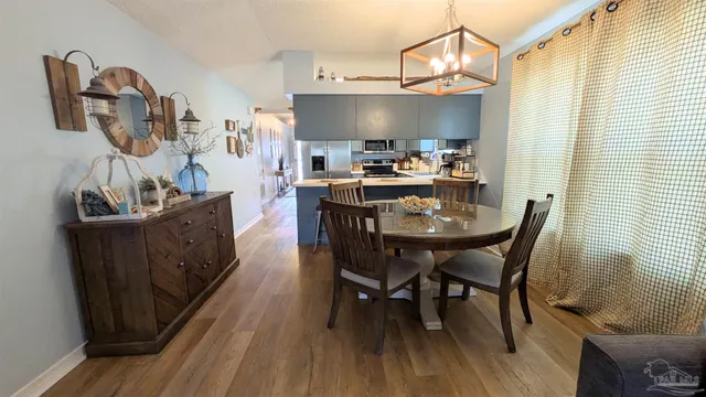a kitchen with stainless steel appliances a dining table chairs and wooden floor