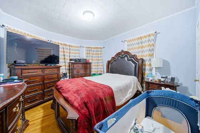 a bedroom with bed and a flat tv screen on dresser
