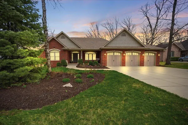 a front view of a house with a garden and trees