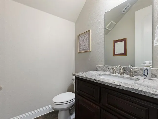 a bathroom with a granite countertop toilet and a sink