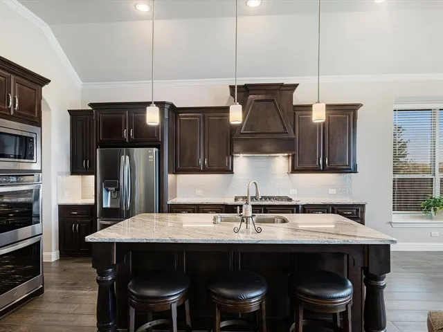 a kitchen with stainless steel appliances a table chairs in it and wooden floors
