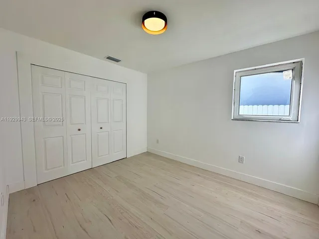 a view of an empty room with window and wooden floor