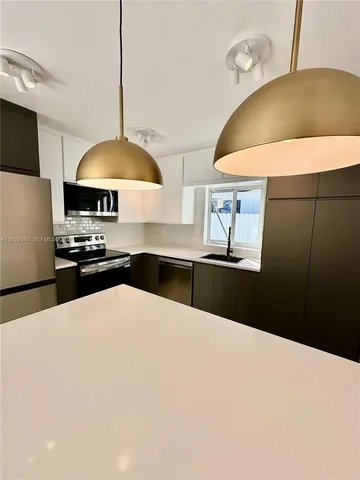 a kitchen with stainless steel appliances a stove a refrigerator a sink a counter space and wooden floor