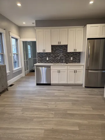 a kitchen with stainless steel appliances granite countertop a refrigerator stove a sink and white cabinets