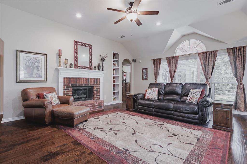 2314 Ranch Road Sachse, TX 75048 - Photo 15 of 27 Living area with vaulted ceilings, recessed lighting, wood-finish flooring, a brick fireplace with a white mantel, and built-in shelving