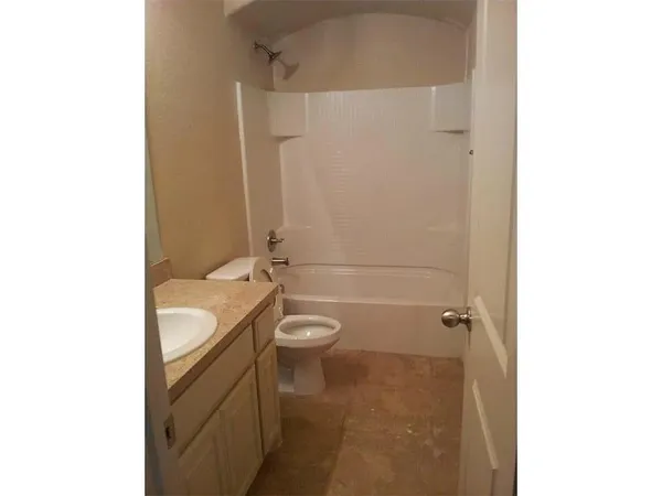 a bathroom with a granite countertop bathtub shower sink mirror and toilet
