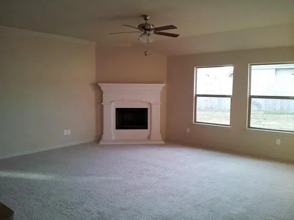 an empty room with windows and fireplace
