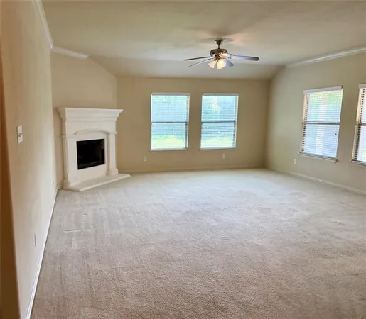 an empty room with chandelier fan and windows