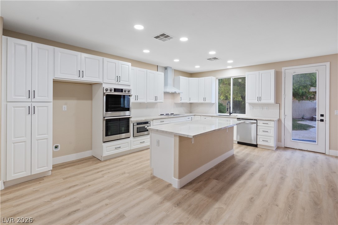 1662 Ravanusa Drive Henderson, NV 89052 - Photo 11 of 74 A well-lit kitchen with sleek white cabinetry, gleaming countertops, and durable flooring.