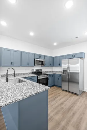 a kitchen with kitchen island granite countertop a sink a counter top space appliances and cabinets