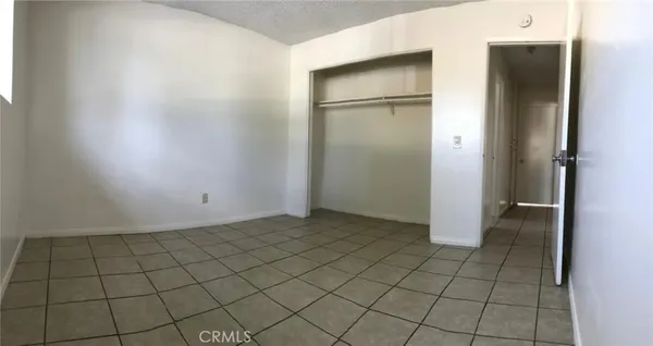 a view of a refrigerator in kitchen and an empty room