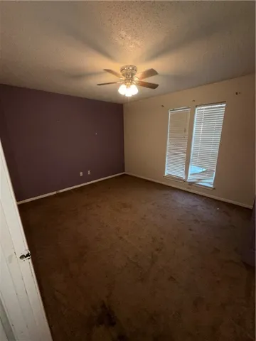 an empty room with a ceiling fan and a window