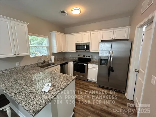 a kitchen with stainless steel appliances granite countertop a sink stove refrigerator and microwave