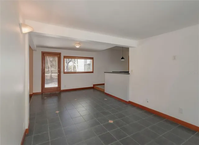a view of an empty room with window and wooden floor