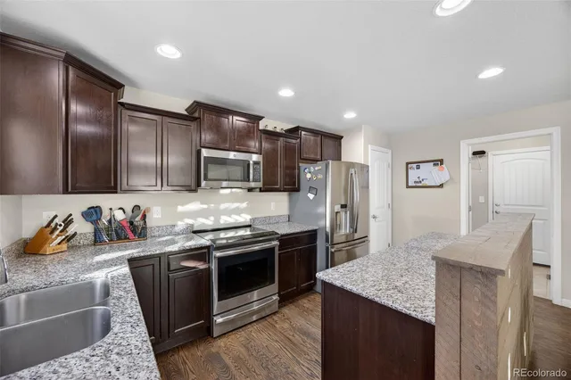 a kitchen with granite countertop a refrigerator and a stove top oven