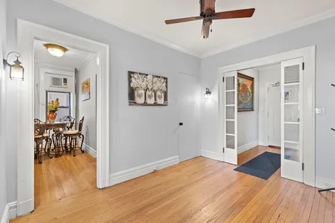 a bedroom with wooden floor and a ceiling fan