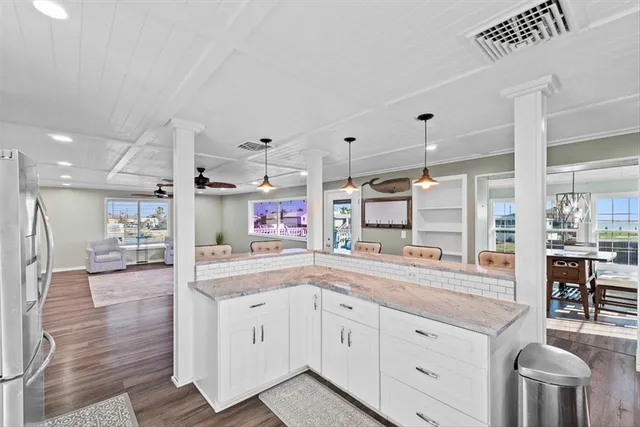 a large white kitchen with a lot of counter space and wooden floor