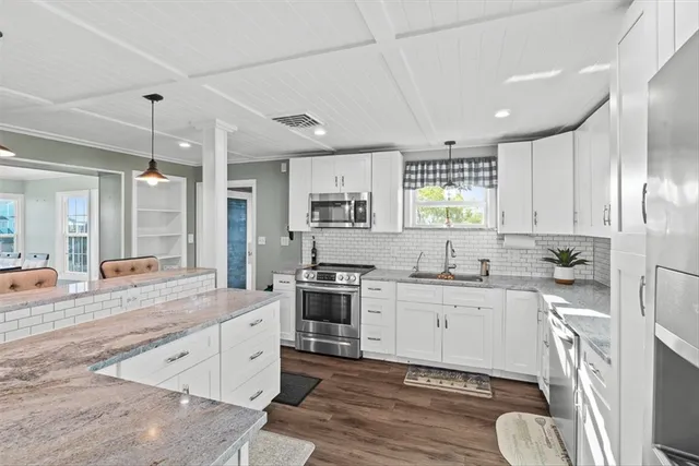 a large kitchen with a stove a sink dishwasher a dining table and chairs with wooden floor