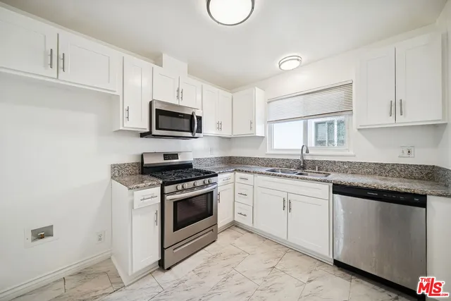 a kitchen with granite countertop a stove sink and cabinets
