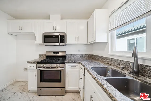 a kitchen with granite countertop a stove top oven microwave and cabinets