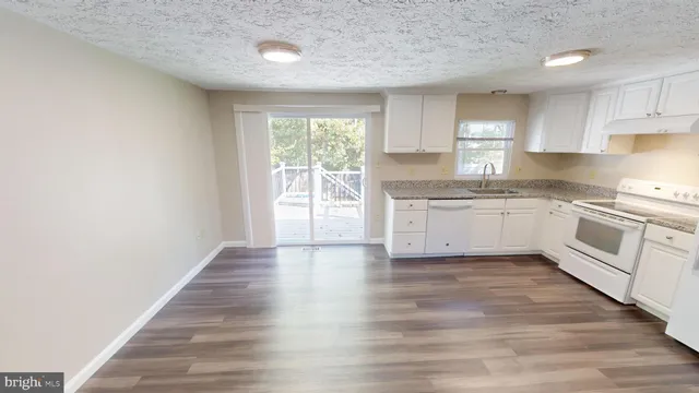 a kitchen with granite countertop white cabinets and white appliances