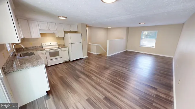 a kitchen with granite countertop a sink window and cabinets