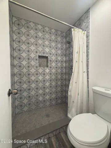 a white toilet sitting next to a shower curtain