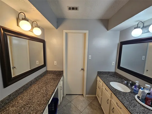 a bathroom with a granite countertop double vanity sink and a mirror