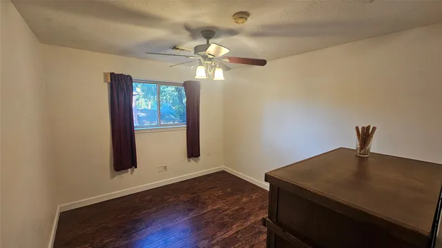 a view of workspace with wooden floor chandelier fan and window