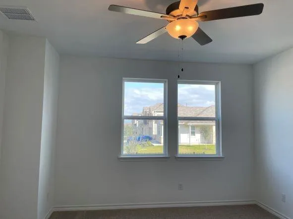 an empty room with a chandelier fan and wooden floor