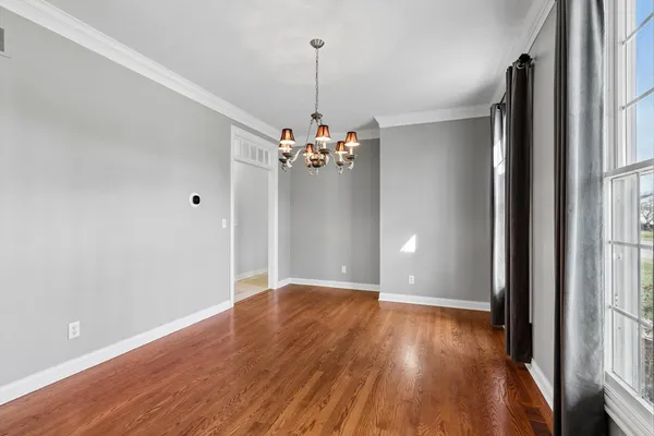 a view of a hallway with wooden floor and a bathroom