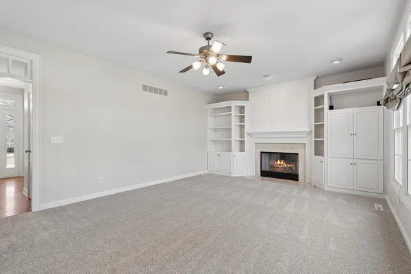 a view of a livingroom with a ceiling fan a fireplace and windows
