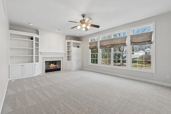 a view of a livingroom with a fireplace a ceiling fan and windows